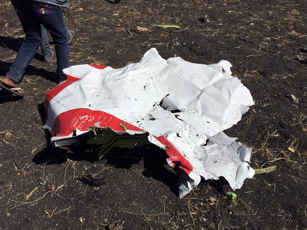 People walk past a part of the wreckage at the scene of the Flight ET 302 plane crash, near the town of Bishoftu