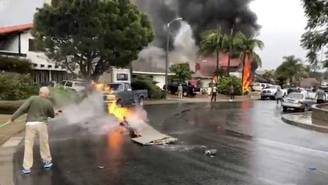 A man puts out fire on a piece of debris from a plane that crashed into a house in a residential neighborhood in Yorba Linda, California