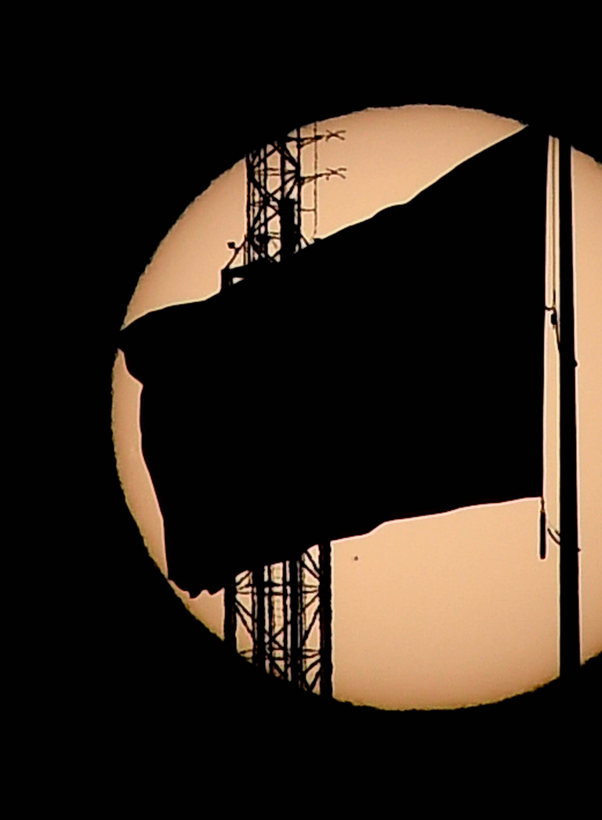 An American flag is silhouetted as the planet Mercury is seen, lower left quadrant, transiting across the face of the sun in Las Vegas