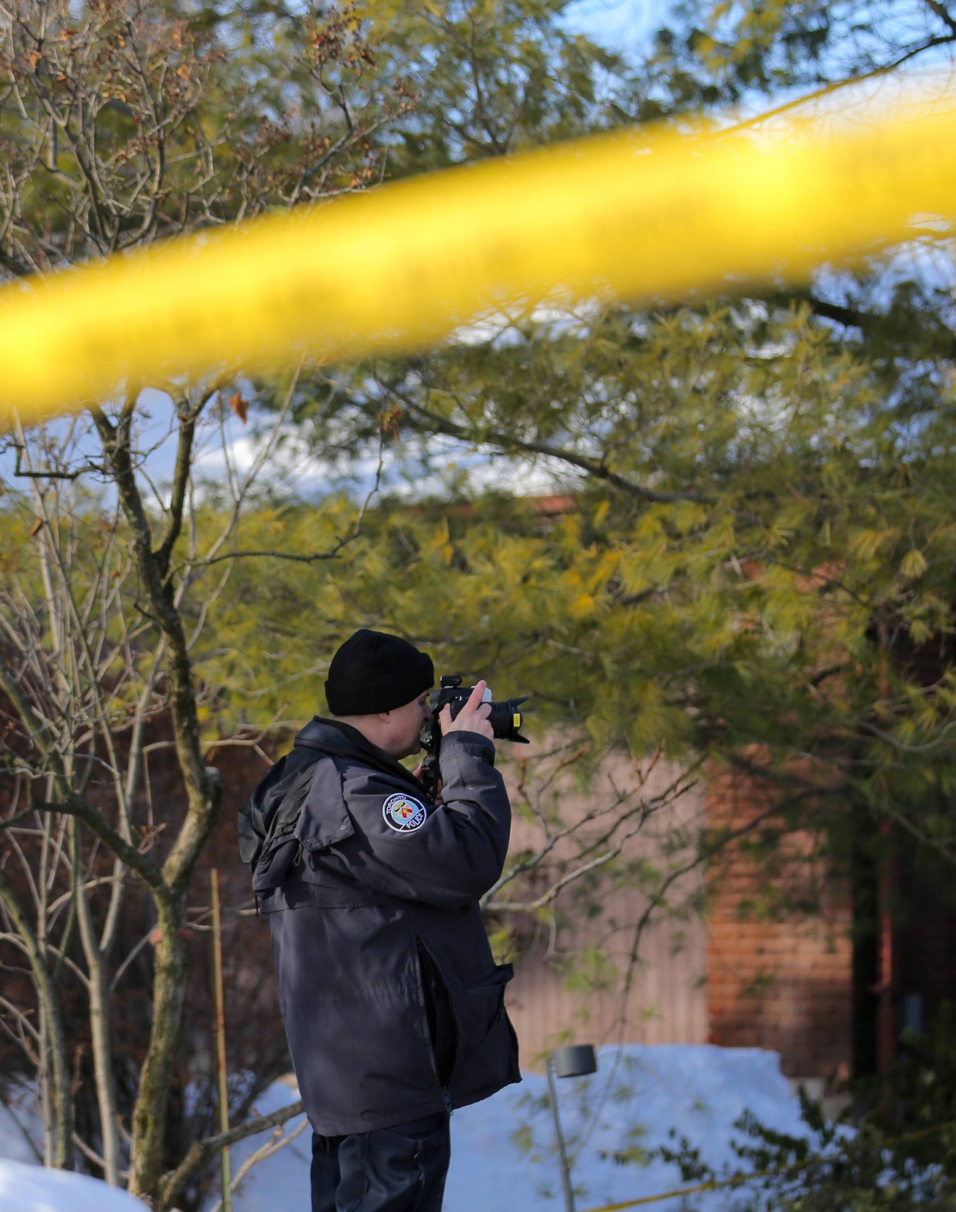 A police forensics photographer works outside the home of billionaire founder of Canadian pharmaceutical firm Apotex Inc. in Toronto