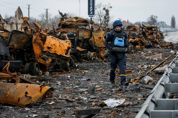 Ukrainian sapper holds the remains of a shell as he works near burned column of military vehicles, on a highway in Kyiv region