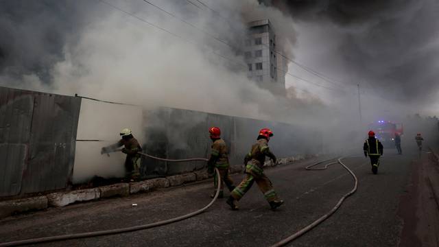 Firefighters extinguish fire at a warehouse that caught flames, according to local authorities, after shelling, in the Kyiv region