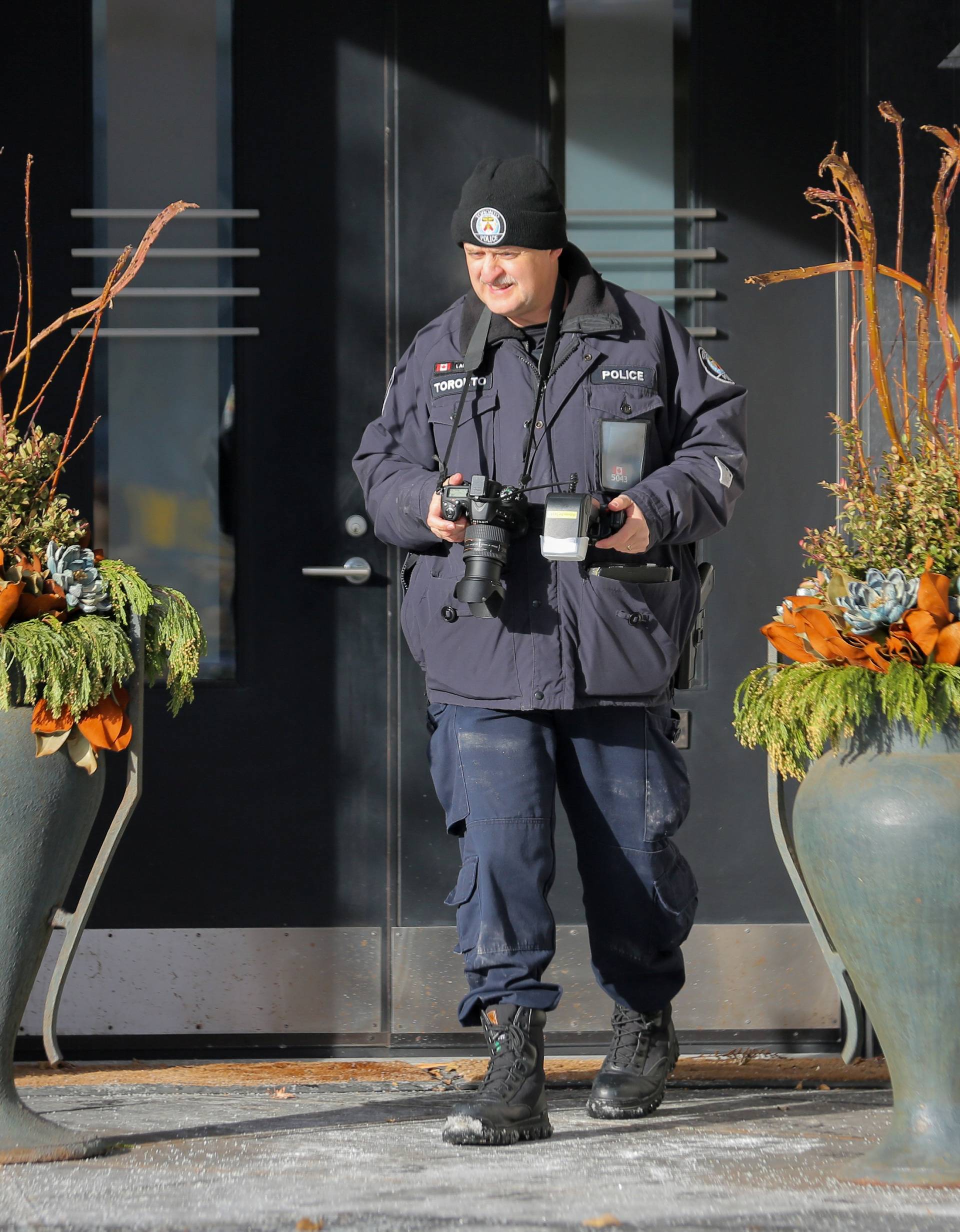 A police forensics photographer works outside the home of billionaire founder of Canadian pharmaceutical firm Apotex Inc. in Toronto