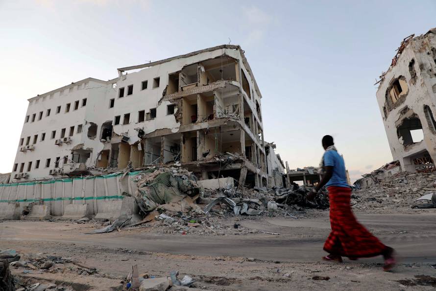A man walks near damaged buildings after a suicide car bomb exploded, targeting a hotel in a business center in Maka Al Mukaram street, Mogadishu