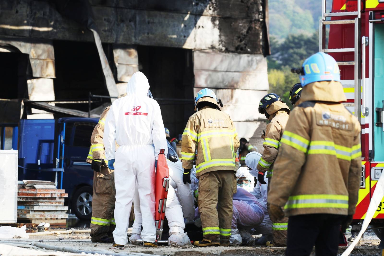 Firefighters and rescue workers check the condition of a survivors rescued from a warehouse which is currently under construction, after it caught fire, in Icheon