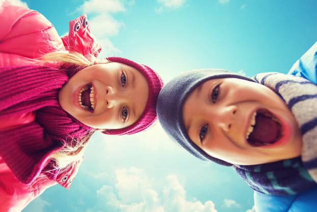 happy little boy and girl faces over blue sky