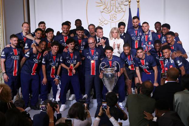 French President Emmanuel Macron and his wife Brigitte Macron, pose with the PSG team after the team won the Champions League, in Paris