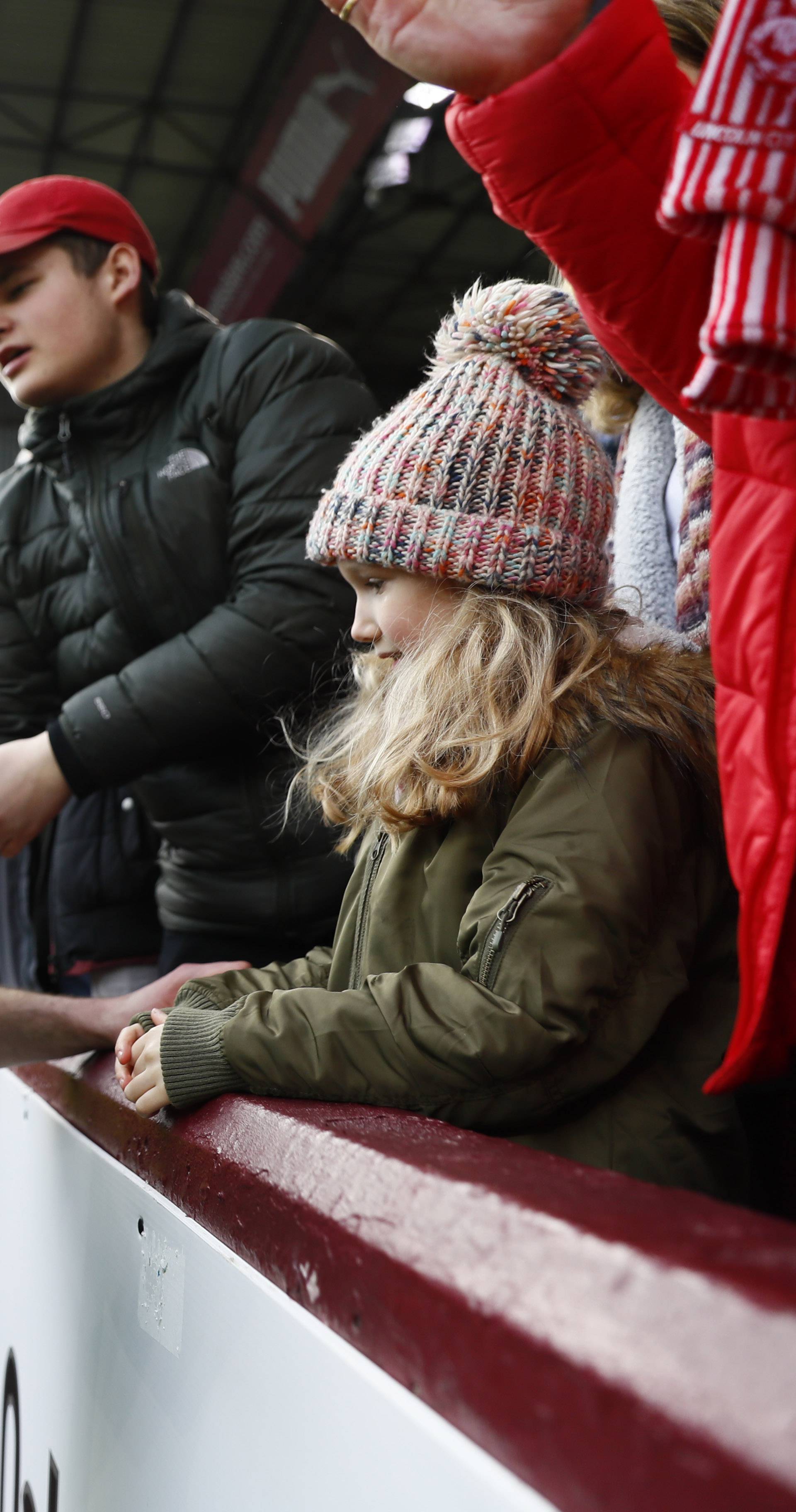 Lincoln's Jamie McCombe celebrates after the match with a young girl