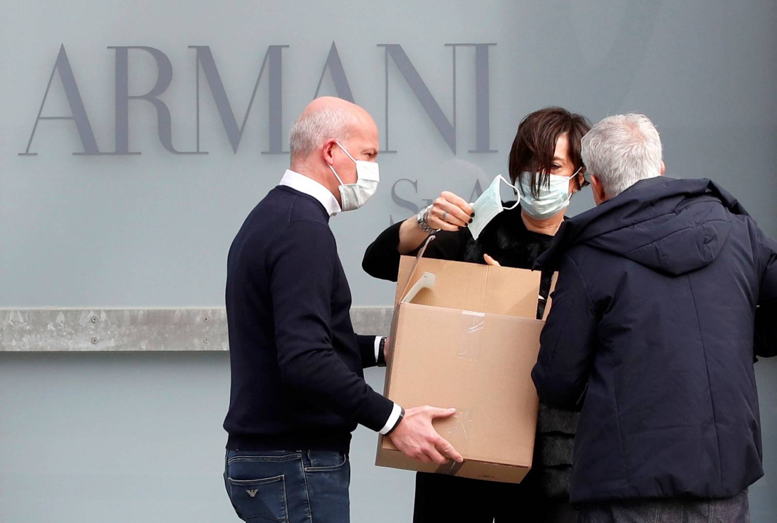 A worker holds a face mask outside the theatre where the Italian designer Giorgio Armani said his Milan Fashion Week show would take place in Milan
