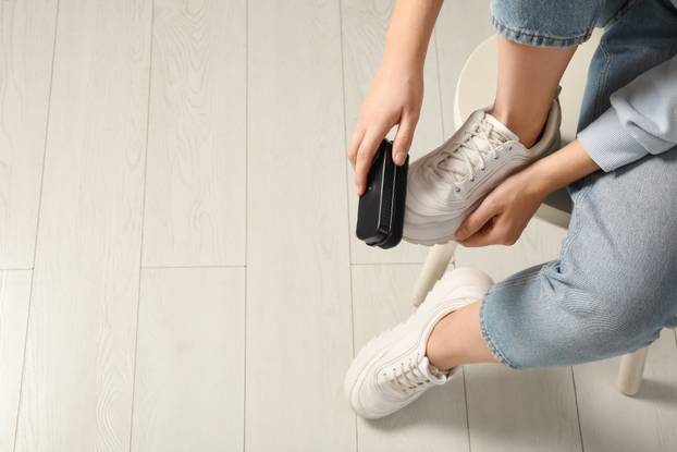 Woman cleaning stylish footwear indoors, closeup. Shoe care acce