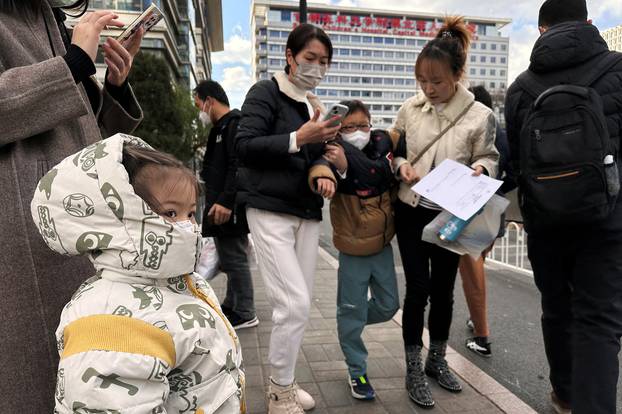 People and children leave a children's hospital in Beijing