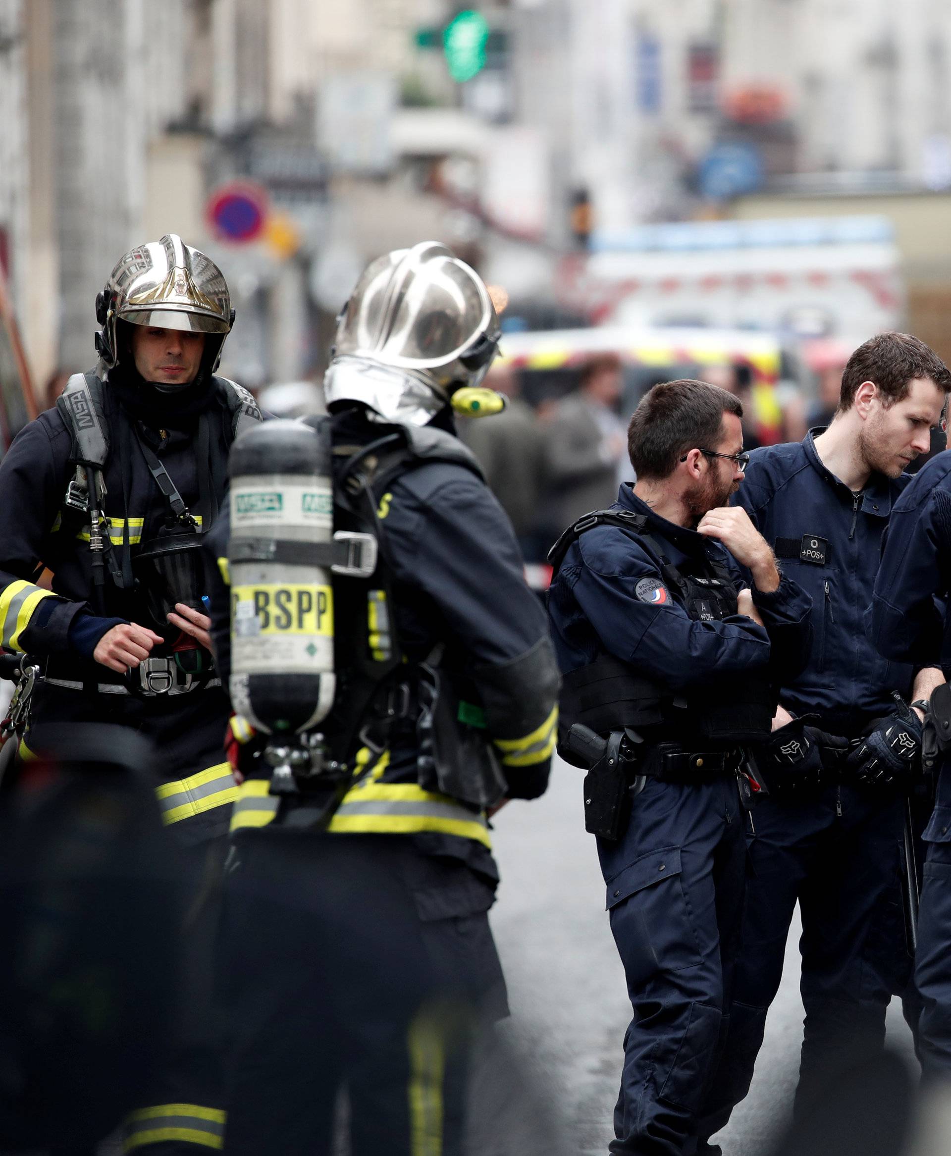 French police and firemen secure the street as a man has taken people hostage at a business in Paris