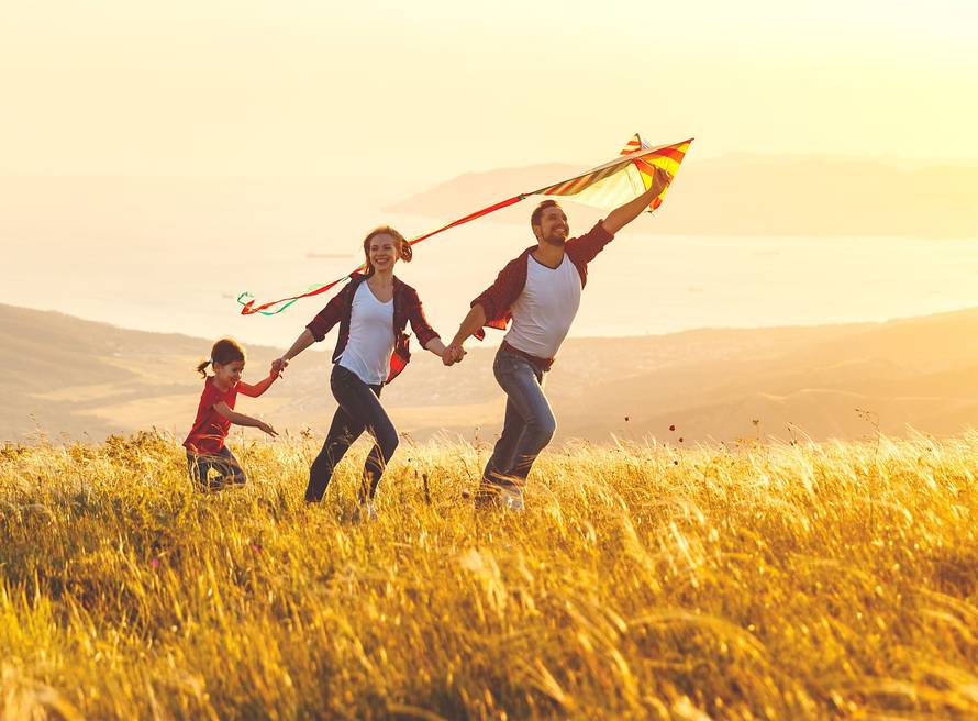 Happy family father,  mother and child daughter launch a kite on nature at sunset