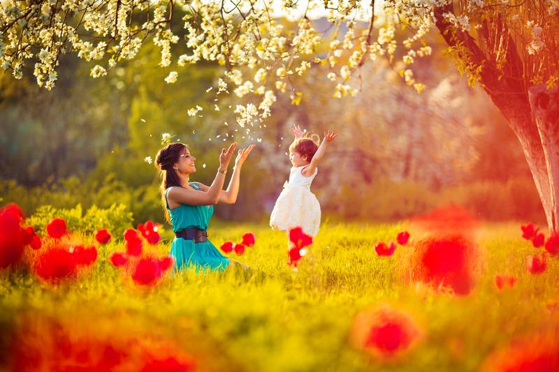 Happy woman and child in the blooming spring garden.Mothers day