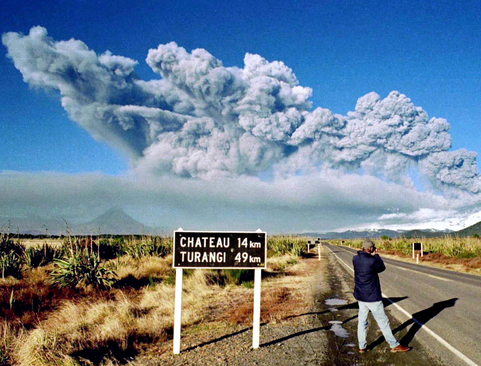 A tourist takes pictures of Mount Ruapehu as it erupts on June 18, 1996 in Tongariro National Park on the central North Island of New Zealand