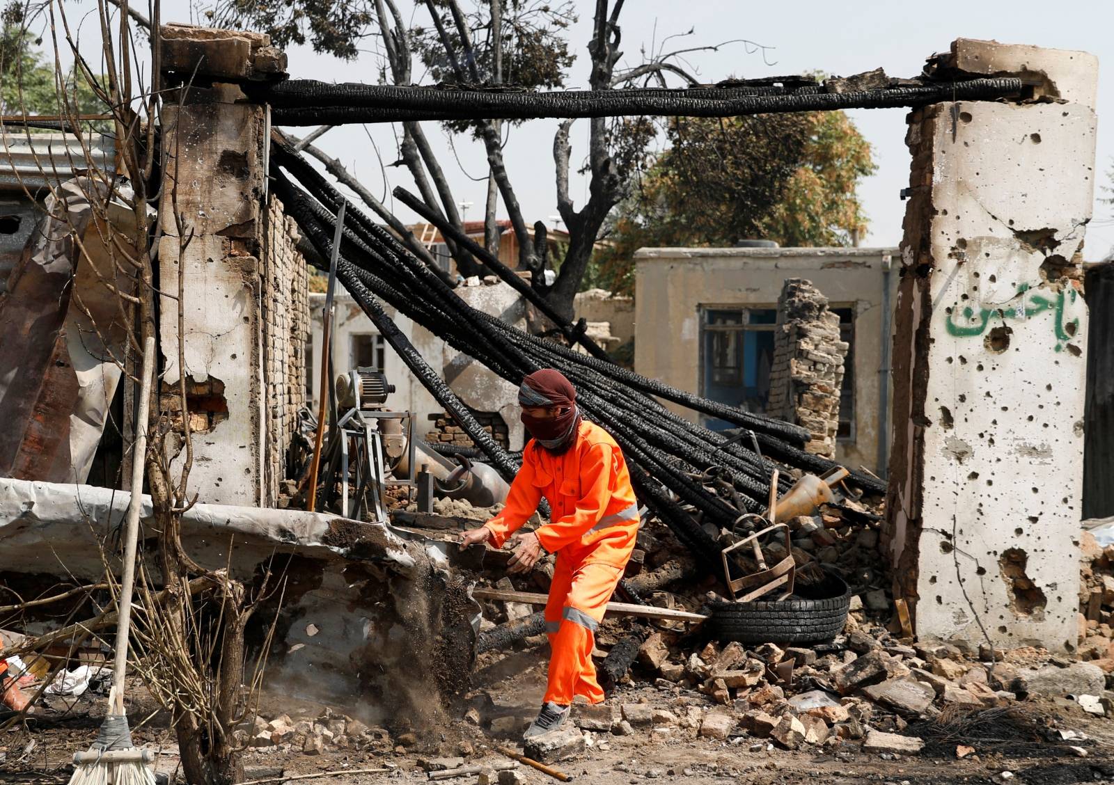 Afghan municipality worker clean debris from a damaged shop at the site of a blast in Kabul