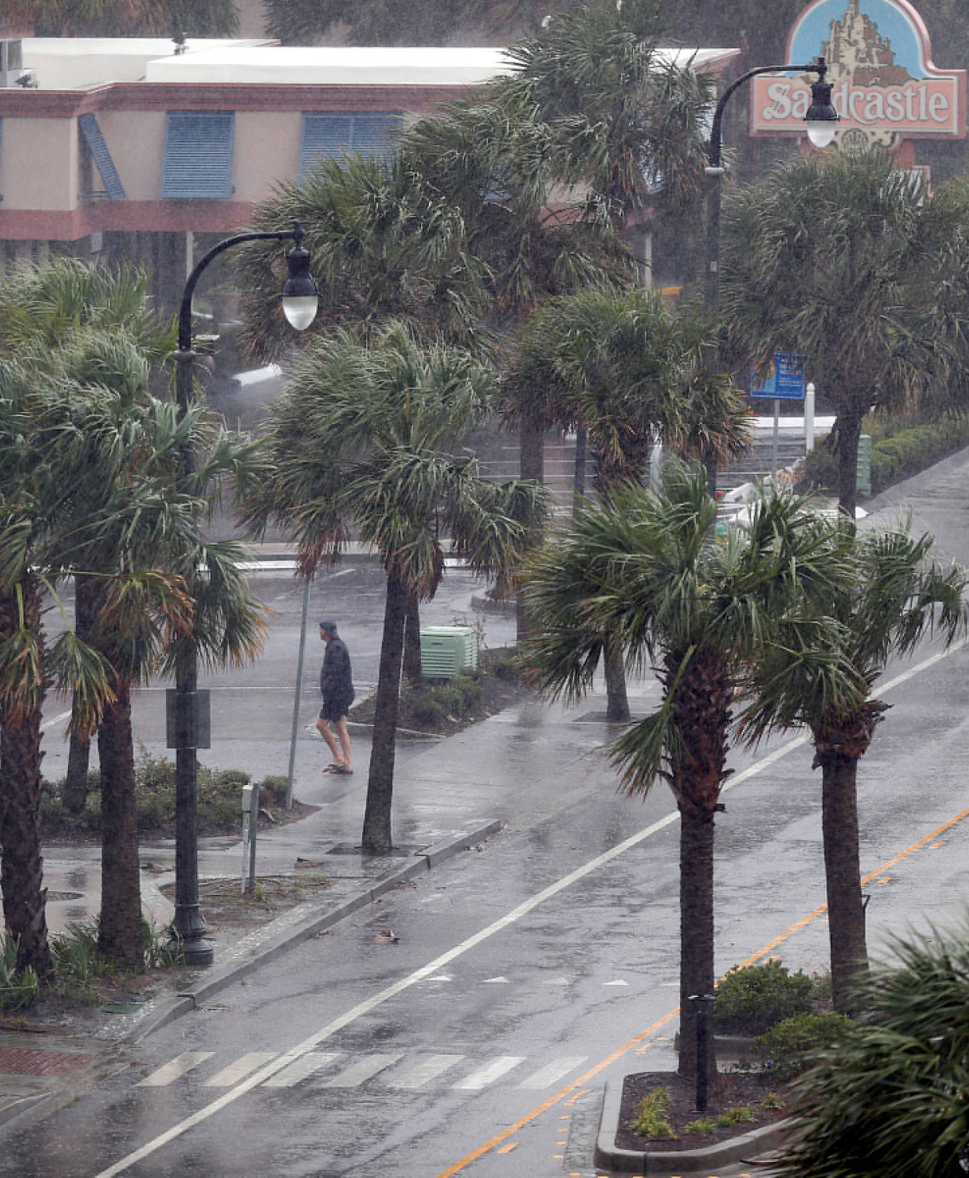 A man walks across Ocean Boulevard during Hurricane Florence in Myrtle Beach