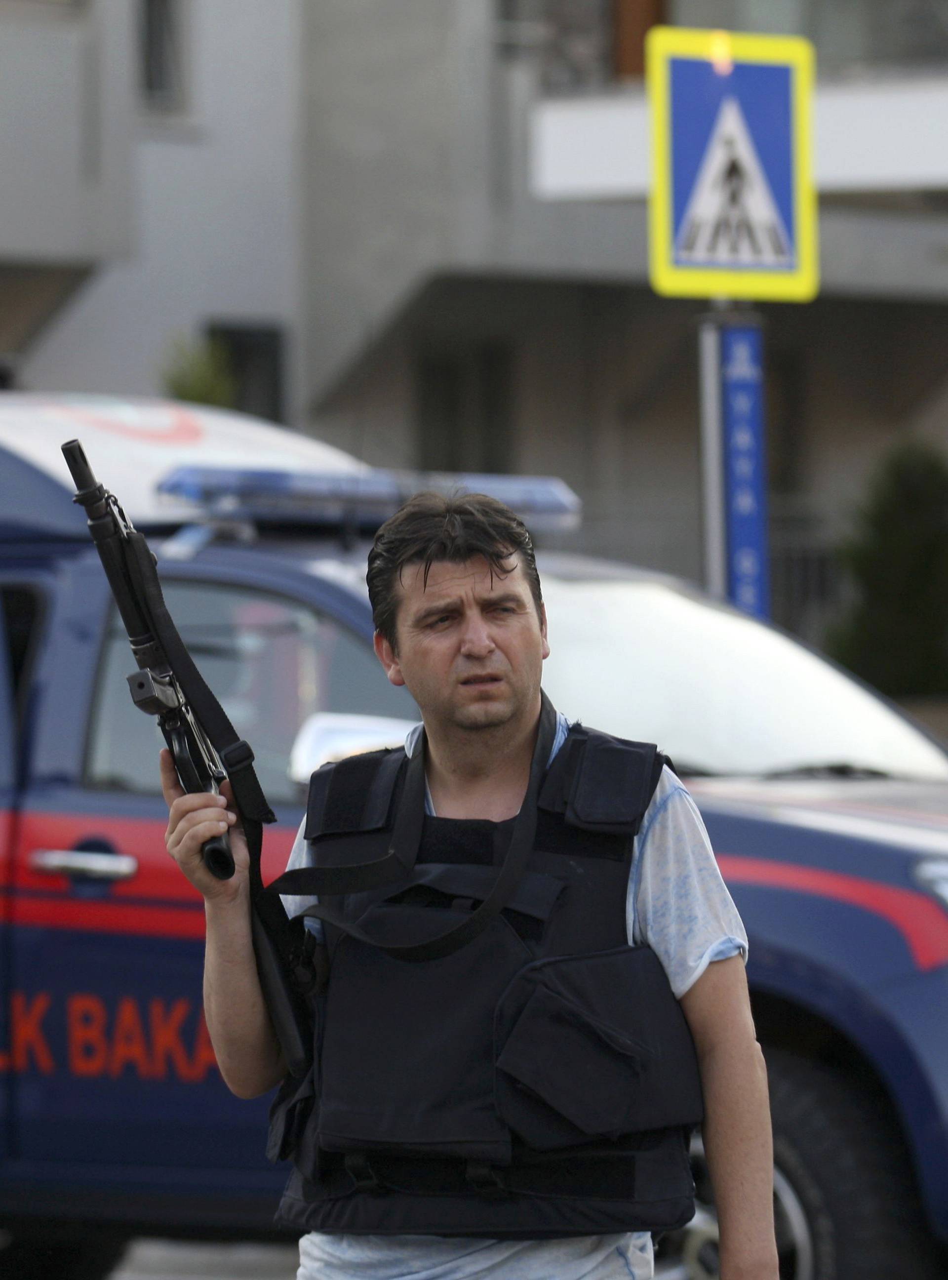 A plain clothes policeman holds a weapon in front of a police vehicle in the resort town of Marmaris