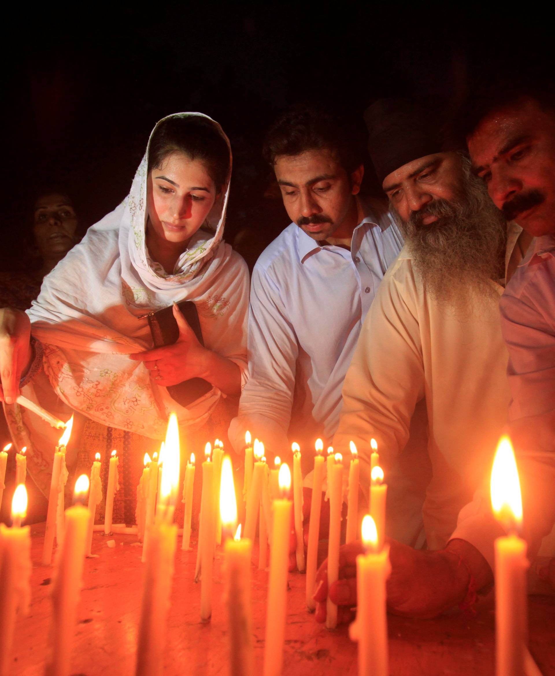 Residents light candles to honour victims of the blast in Quetta during a candellight vigil in Peshawar