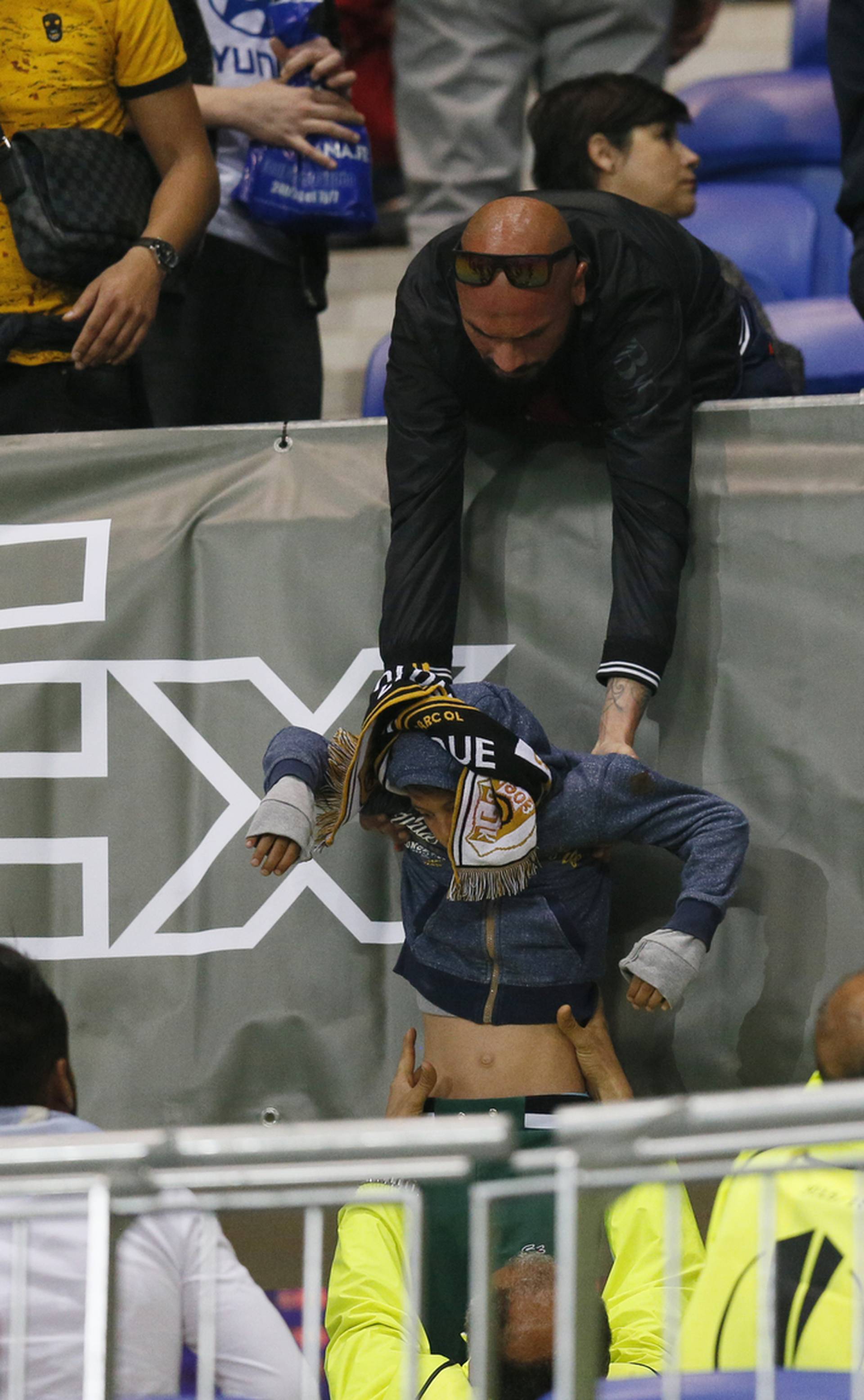 A Lyon fan helps another fan out of the stands as fans clash