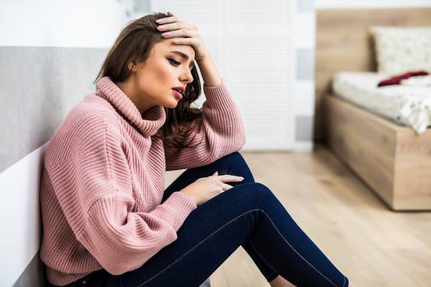 beautiful woman feeling bad and getting headache painful sitting on living room floor