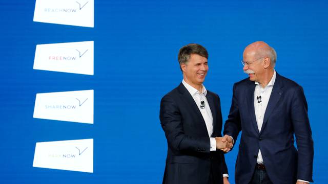 Harald Kruger, CEO and Chairman of the Board of Management of BMW AG and Dieter Zetsche, CEO of Daimler AG, shake hands at a news conference to present plans for combining the companies' car-sharing businesses, in Berlin