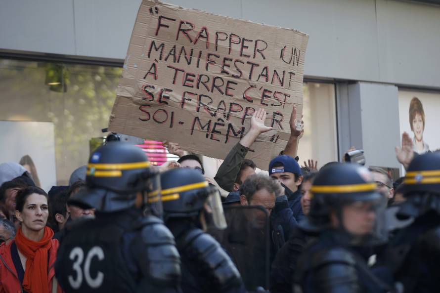  Youths hold a sign which reads, "To strike down a demonstrator is to strike one-self" near French riot police during a protest against the French labour law proposal during the May Day labour union march in Paris