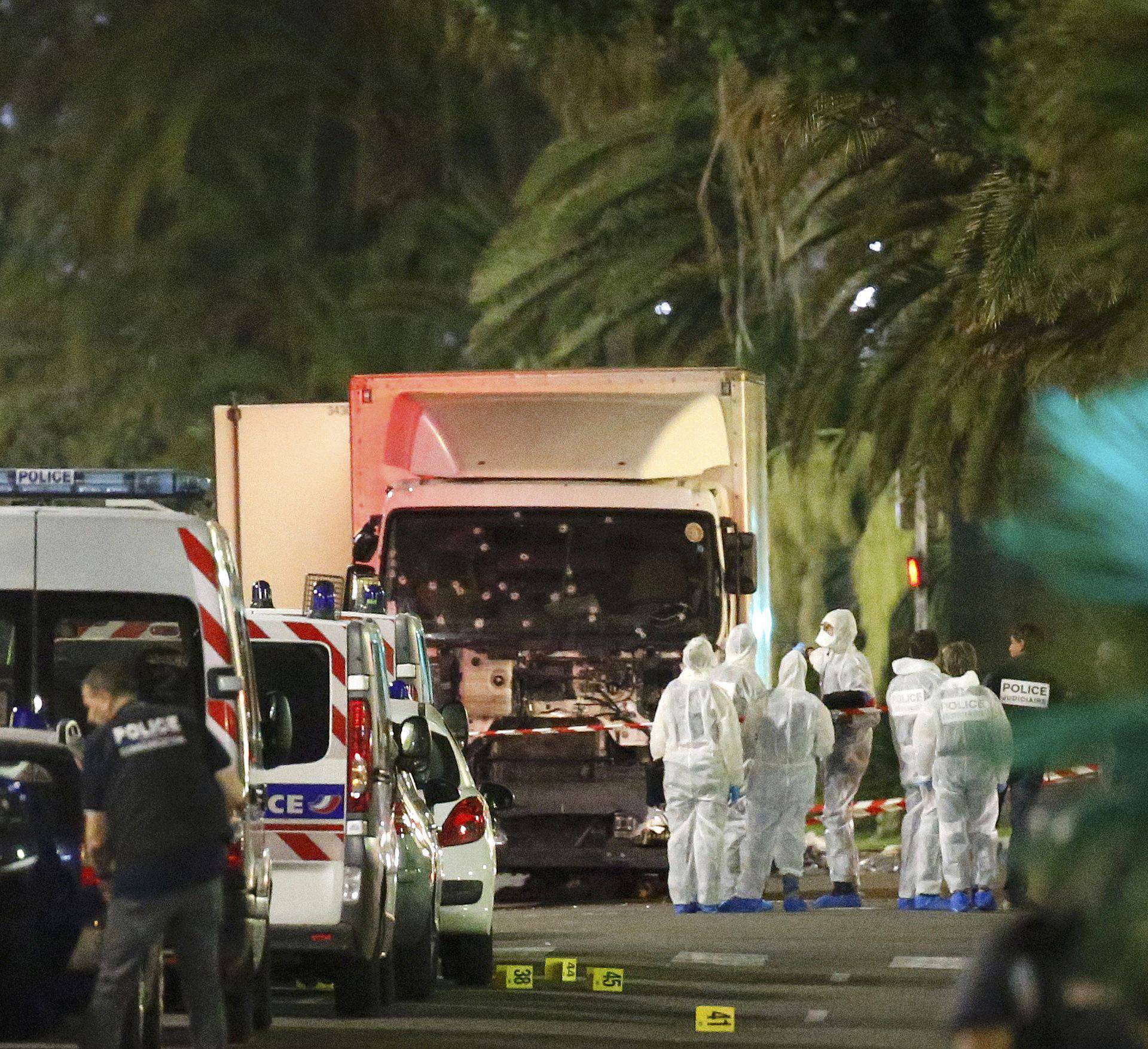 French police forces and forensic officers stand next to a truck that ran into a crowd celebrating the Bastille Day national holiday on the Promenade des Anglais killing at least 60 people in Nice