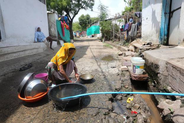 Pranje posuđa na vodovodnoj cijevi u selu Gora u Bhopalu, glavnom gradu indijske savezne države Madhya Pradesh, 22. lipnja 2022. Ruralni projekt opskrbe vodom financira Nova razvojna banka. 