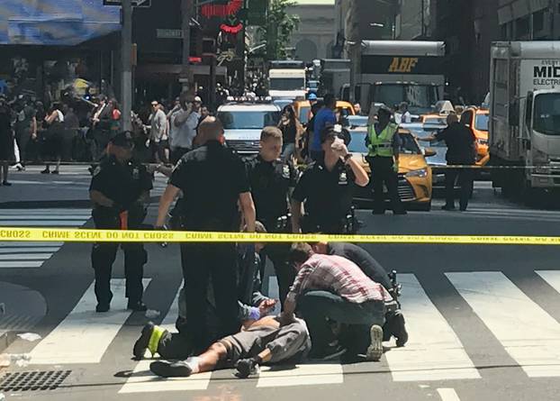 First responders and people help injured pedestrians after a vehicle struck pedestrians on a sidewalk in Times Square in New York