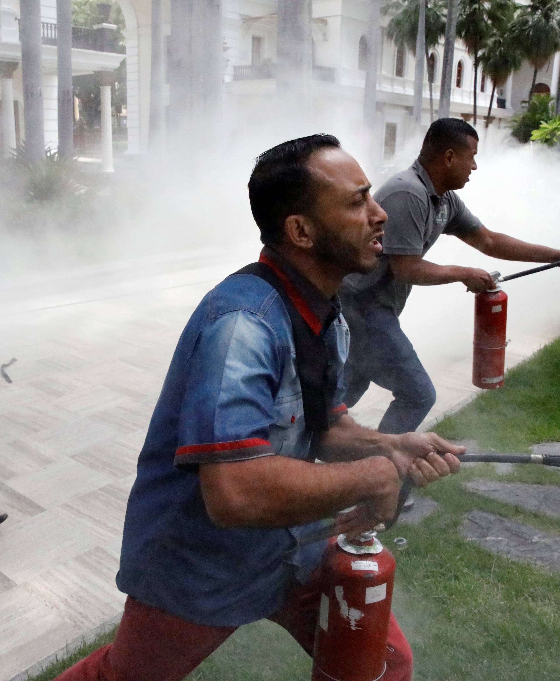 People use fire extinguishers during clashes with government supporters outside the National Assembly, in Caracas