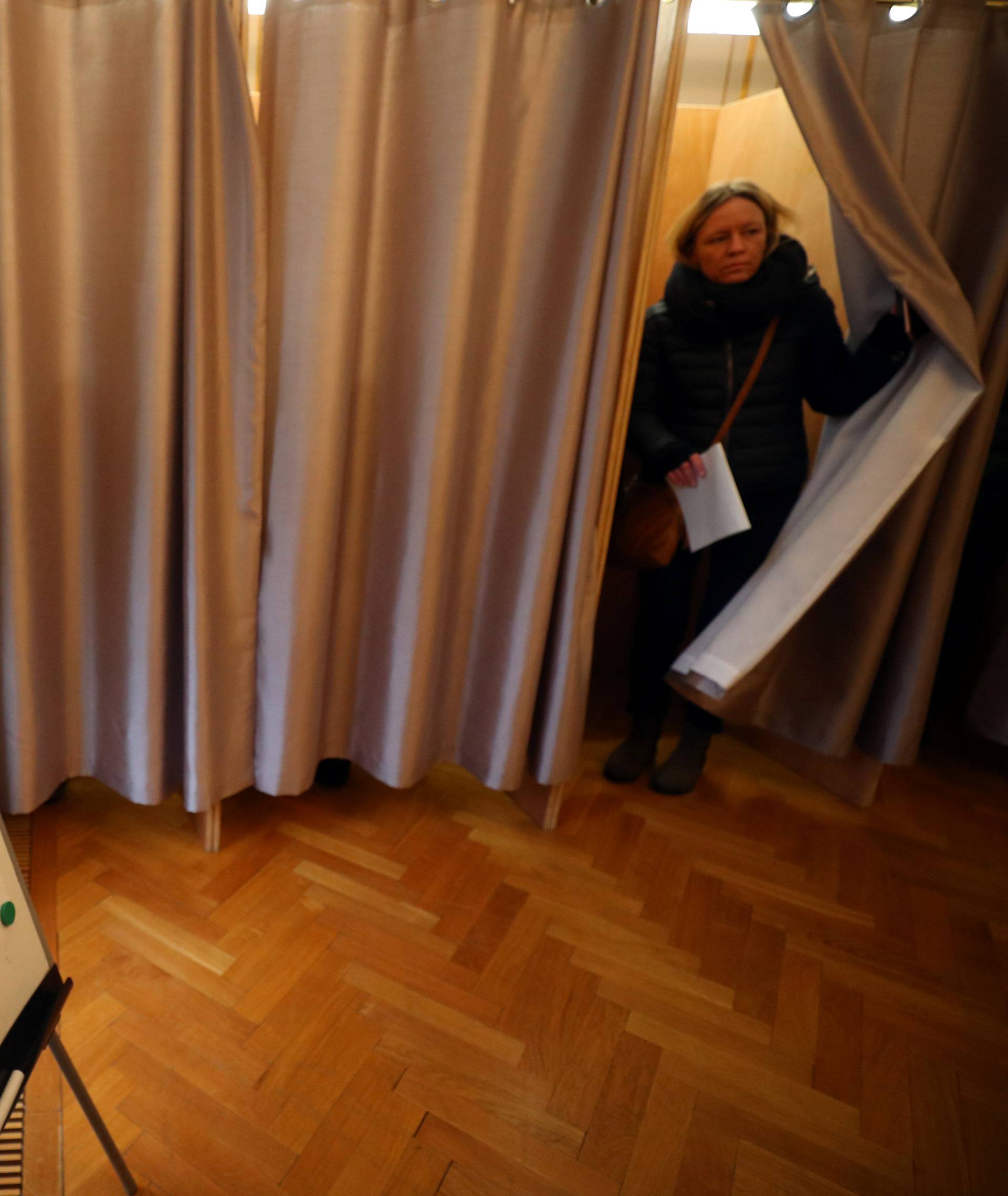 A woman walks out of a voting booth during the presidential election, at the Russian Embassy in London