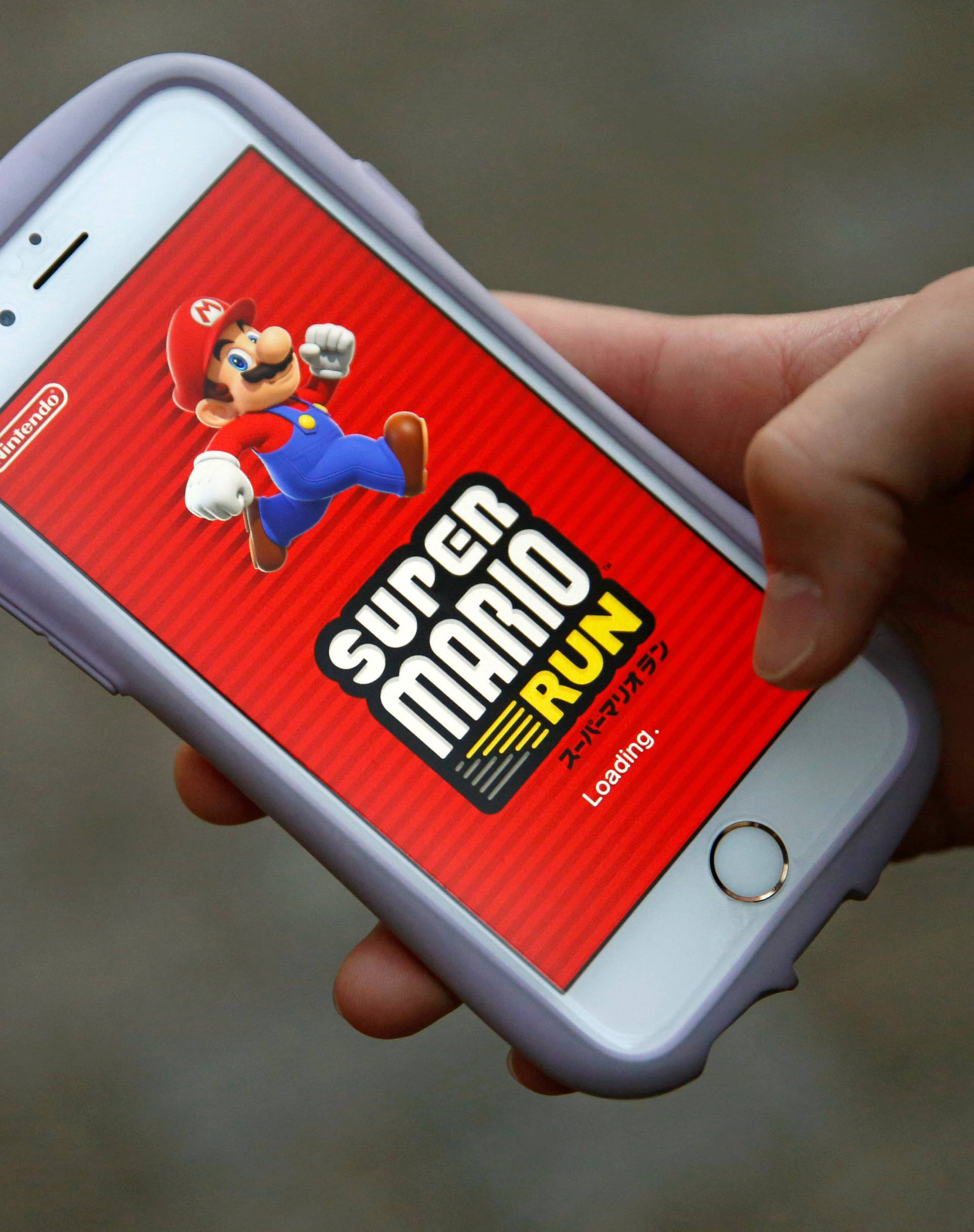 Takuya Nishya shows Nintendo's "Super Mario Run" game on his smartphone by the request of a photographer in Tokyo