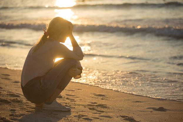 Sad and alone young woman at the beach.