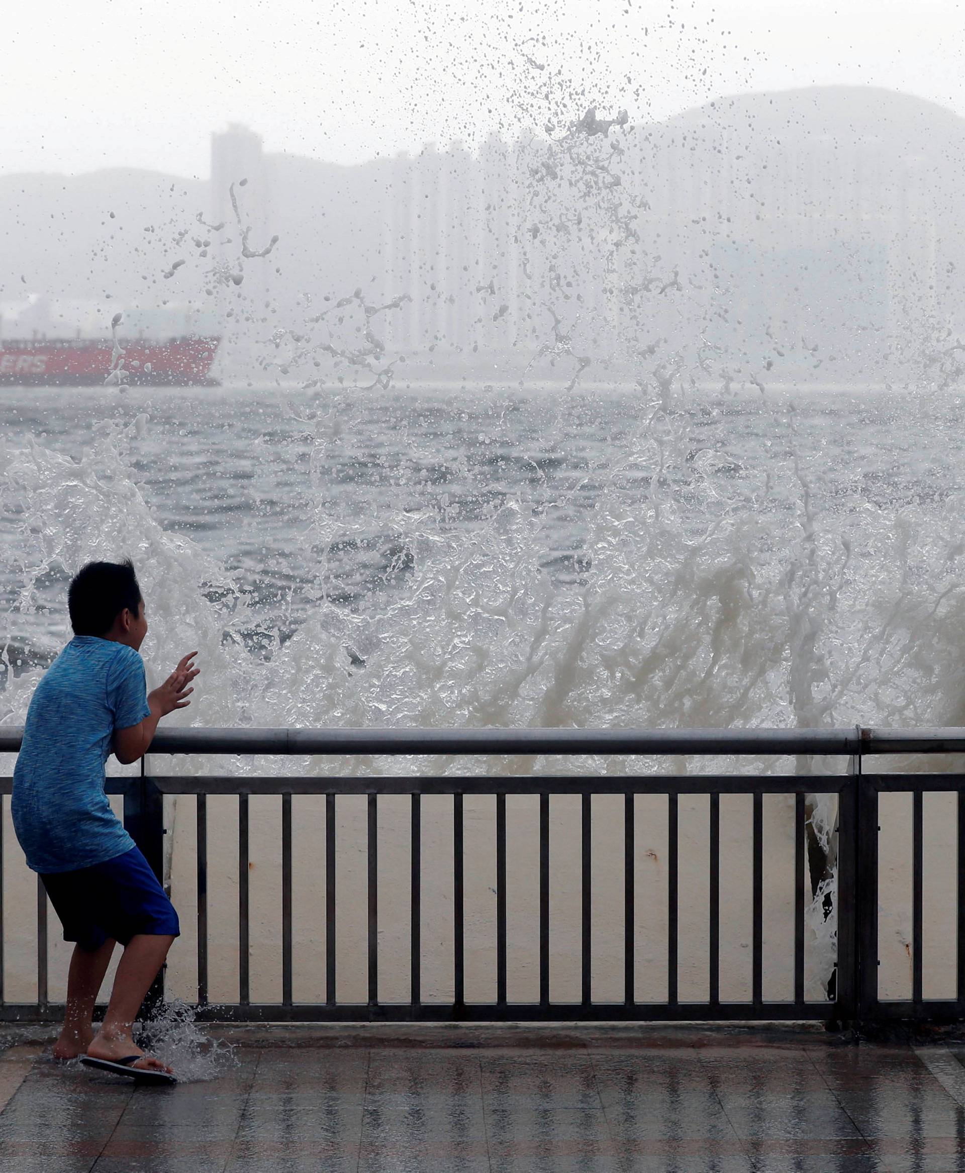 A child reacts after a big wave on a waterfront as Typhoon Hato hits Hong Kong