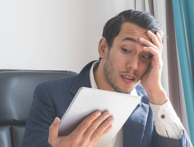 Business man is shock looking at tablet computer