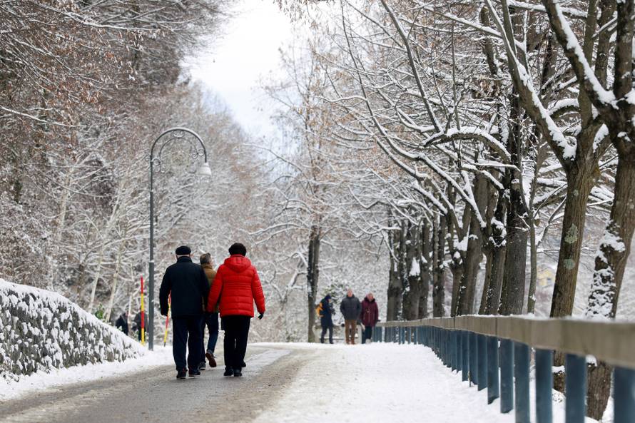 People walk in a snow covered forest in Bled