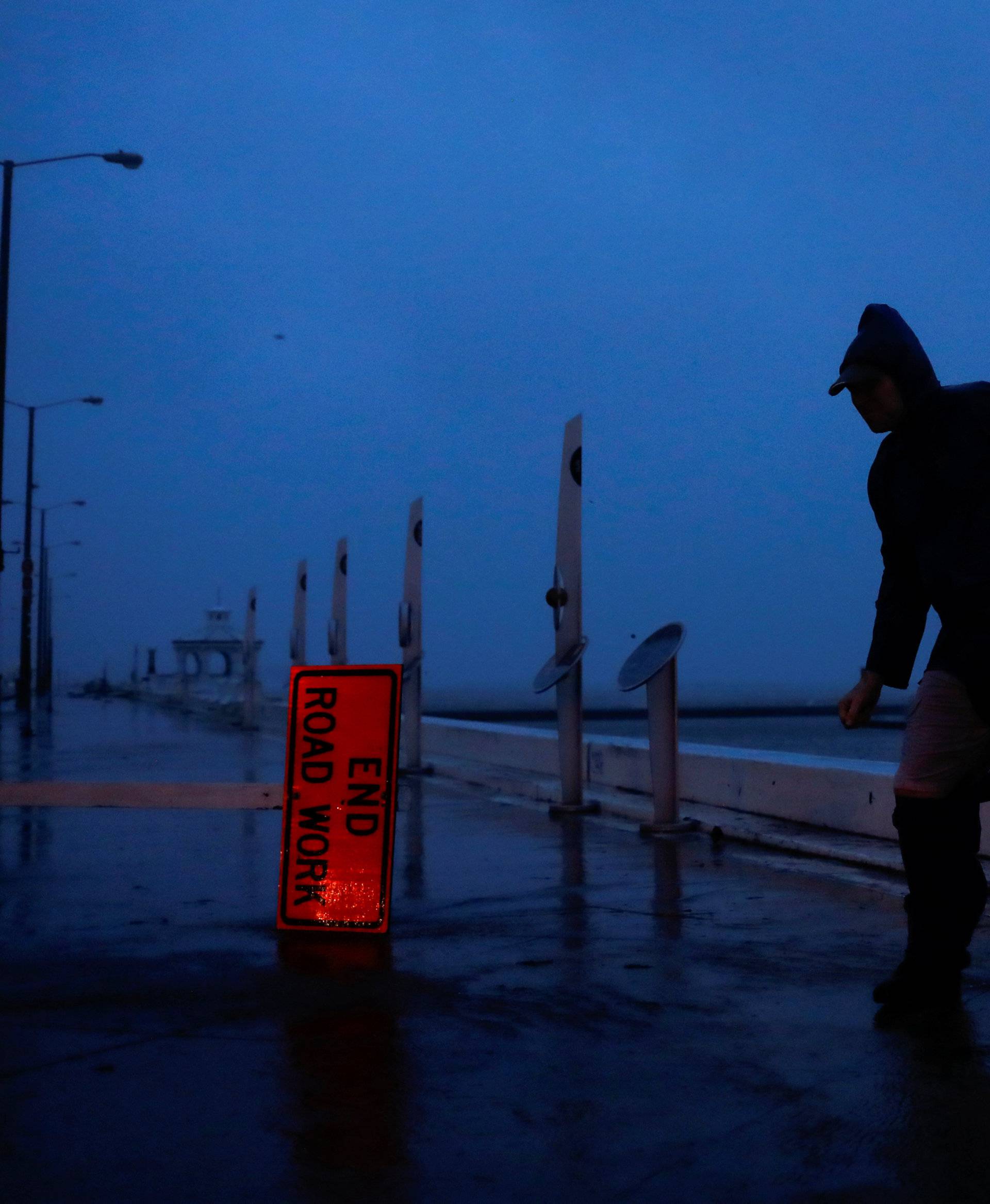 Debris flies past as Stewart Adams, of San Marcos, Texas, balances himself from a gust of wind from Hurricane Harvey along the boardwalk in Corpus Christi,