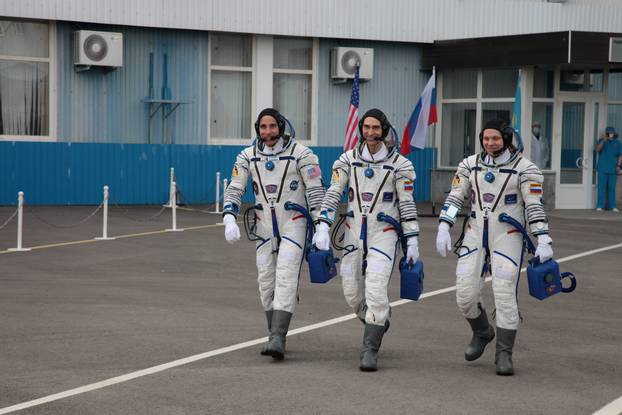 The International Space Station (ISS) crew members walk before leaving to board the Soyuz MS-16 spacecraft for the launch at the Baikonur Cosmodrome