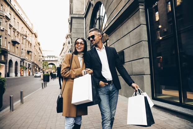 Fashionable,Couple,Walking,In,City,With,Shopping,Bags,,Laughing,And