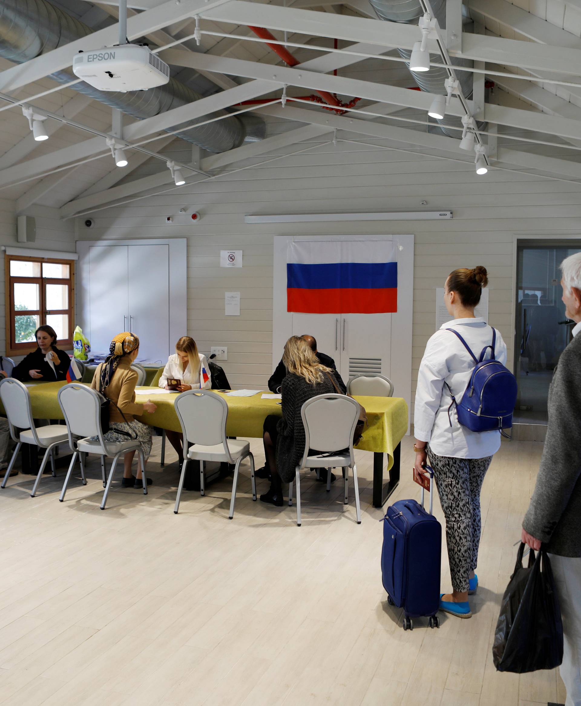 Russian citizens stand in line ahead of casting their ballots for Russia's presidential election in a polling station in Jerusalem