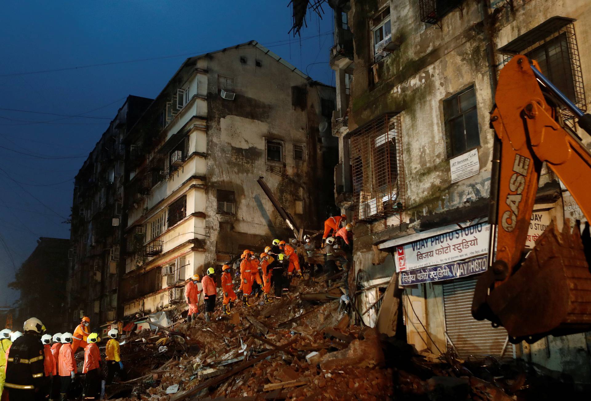 National Disaster Response Force (NDRF) and fire brigade personnel look for survivors trapped in the debris after part of a residential building collapsed following heavy rains in Mumbai