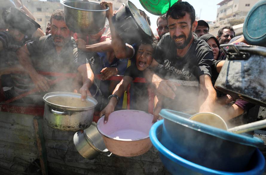 Palestinians wait to receive food from a charity kitchen, in Gaza City