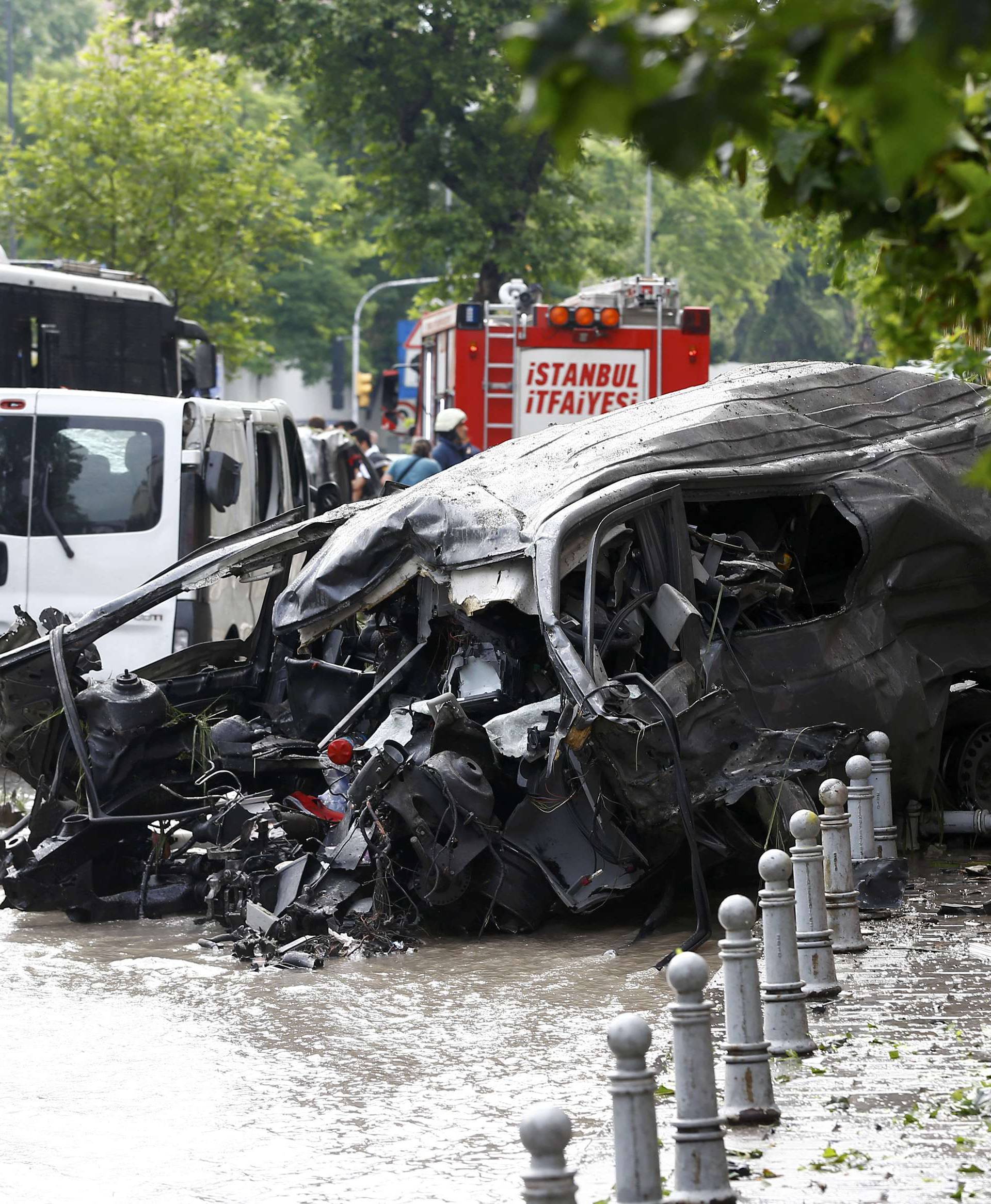 A destroyed van is pictured near a Turkish police bus which was targeted in a bomb attack in a central Istanbul district