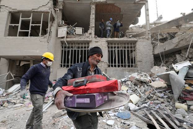 A man gathers the remaining furniture from an apartment damaged by an airstrike, in Tehran