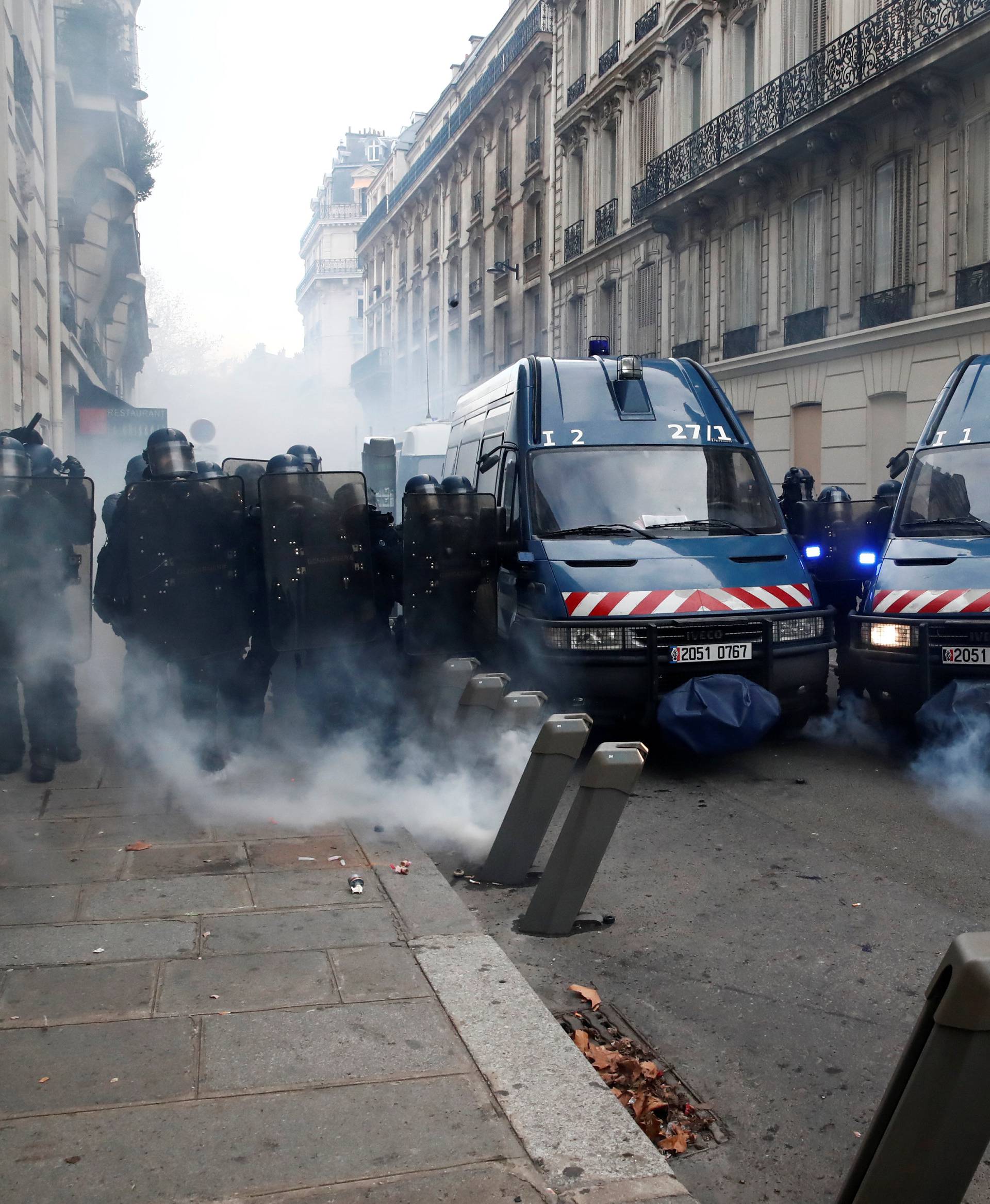 Tear gas floats in the air around French gendarmes who secure a street during a national day of protest by the "yellow vests" movement in Paris