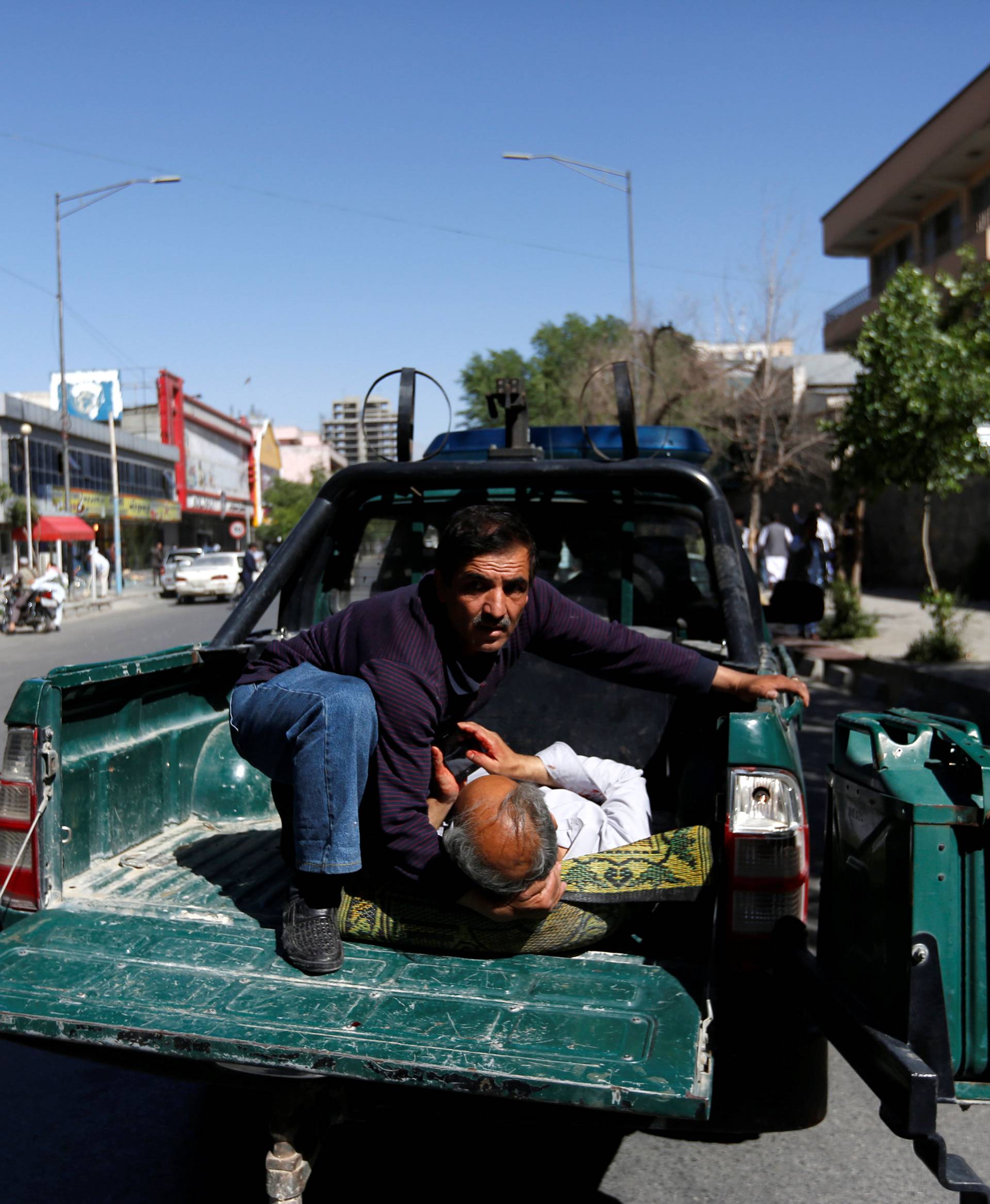 A man holds an injured outside a hospital after a blast in Kabul, Afghanistan