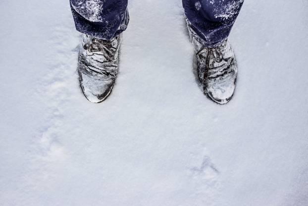 Shoes under snow with text place. Boots offroad winter concept. Top view.