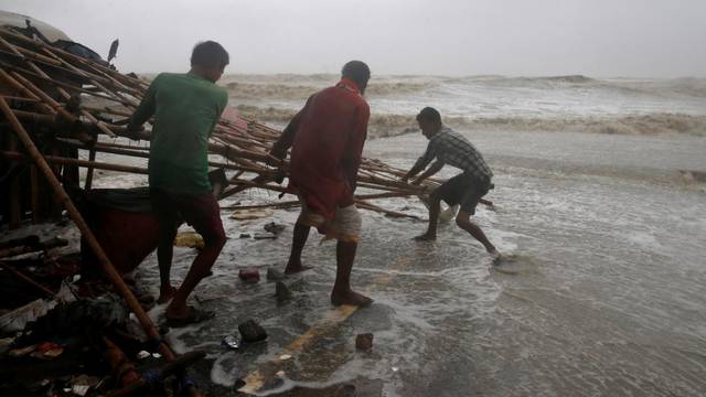 Men remove bamboo rooftop of a stall damaged by heavy winds at a shore ahead of Cyclone Yaas in Bichitrapur