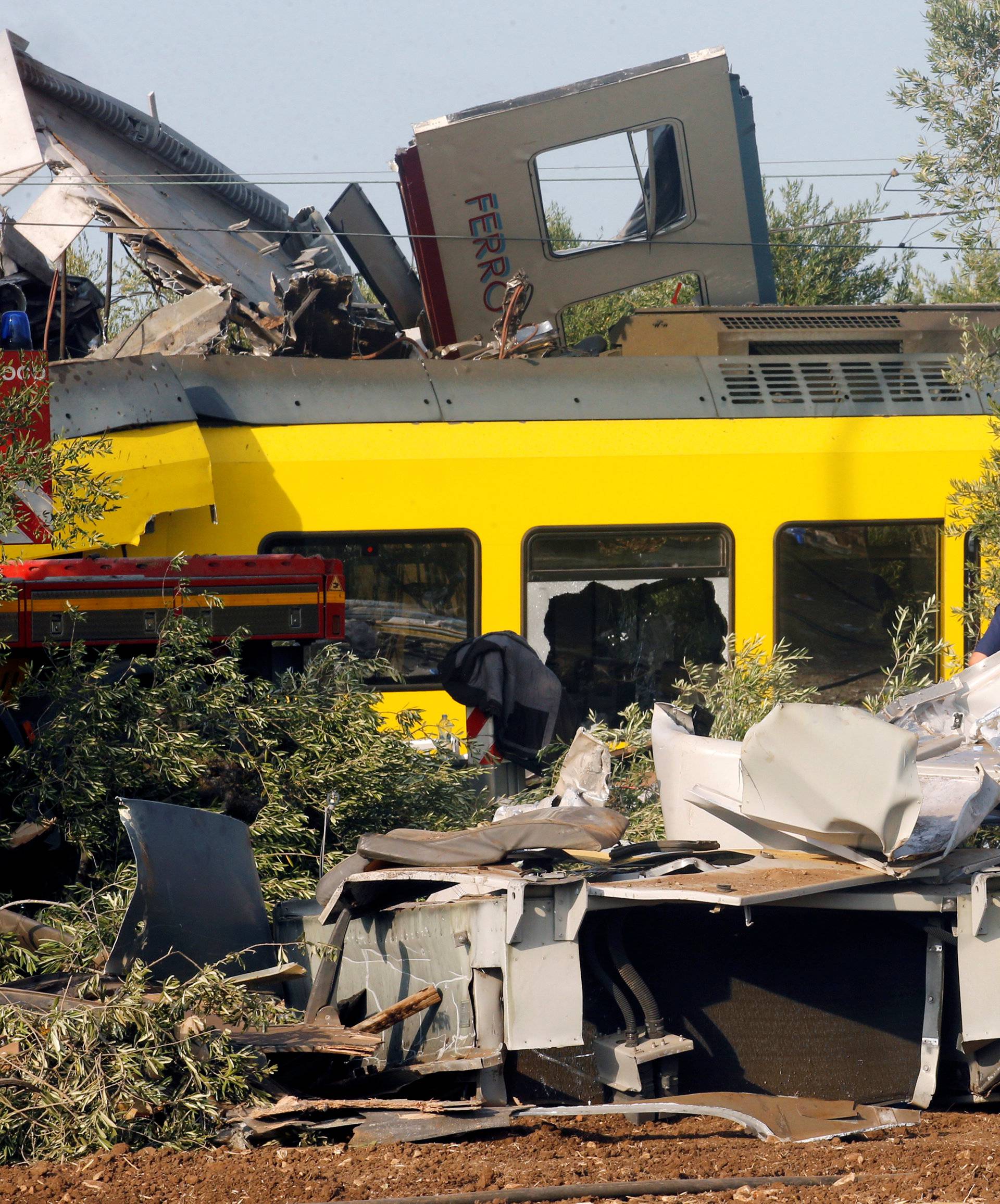 Rescuers stand at the site where two passenger trains collided in the middle of an olive grove in the southern village of Corato